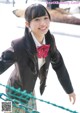 A young woman in a school uniform smiles at the camera.