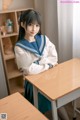 A woman in a school uniform sitting at a desk.