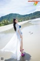 A woman in a white dress standing on a beach.