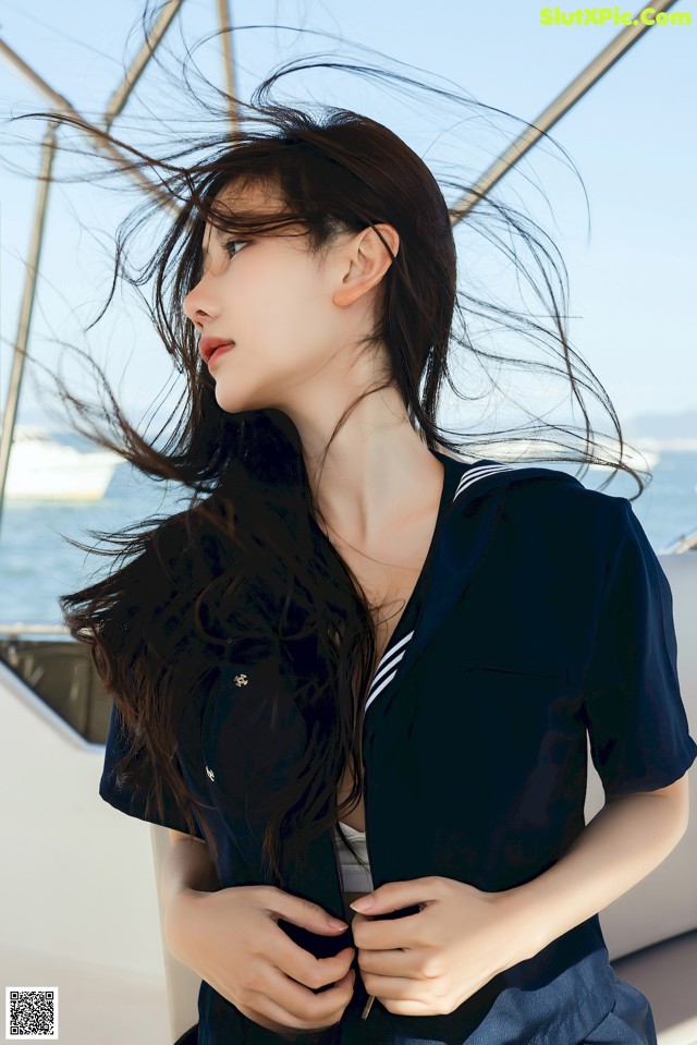 A woman with long black hair standing on a boat.