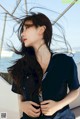 A woman with long black hair standing on a boat.