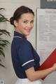 A woman in a blue shirt and white skirt holding a red folder.