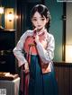 A woman in a hanbok standing in front of a television.