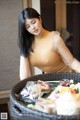 A woman in a yellow top is preparing food on a table.