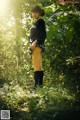 A woman standing in the middle of a lush green forest.