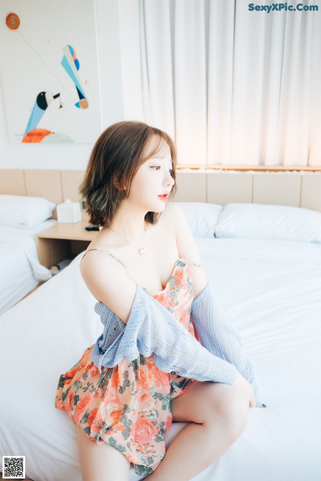 A woman sitting on a bed in a bedroom.