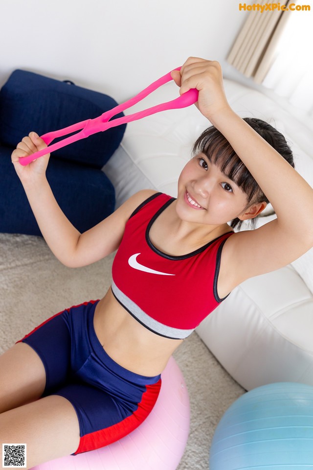 A woman sitting on an exercise ball holding a pink resistance band.