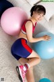 A young woman sitting on the floor next to two exercise balls.