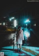 A woman in a white raincoat holding an umbrella in the rain.